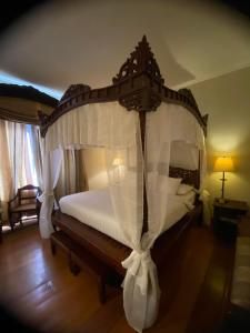 a bedroom with a canopy bed with white curtains at Hotel Salcedo De Vigan in Vigan