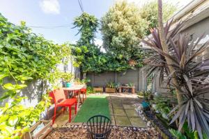 een kleine achtertuin met een tafel, stoelen en planten bij Modern and Stylish 2 BD House in Claremont in Kaapstad