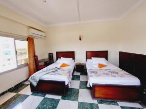 Un dormitorio con dos camas y suelo de baldosas. en Delmon Hotel, en El-Tor