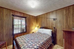 sypialnia z łóżkiem z drewnianymi ścianami i oknem w obiekcie Low Cotton's Quarter w mieście West Point