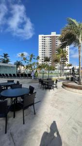 Un patio con mesas y bancos y palmeras. en Salinas Exclusive Resort 1308, en Salinópolis