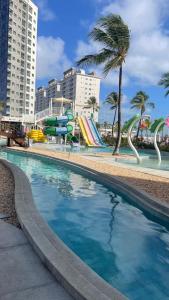 una piscina con toboganes y palmeras en una ciudad en Salinas Exclusive Resort 1308, en Salinópolis
