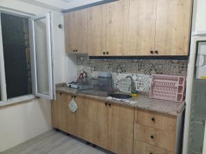 a kitchen with wooden cabinets and a sink and a window at Avcı Pansiyon in Gokceada Town