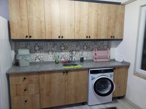 a kitchen with wooden cabinets and a washing machine at Avcı Pansiyon in Gokceada Town