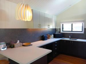 a kitchen with white counters and a light fixture at Hideaway Falls - Staggys Cottage in Mapleton