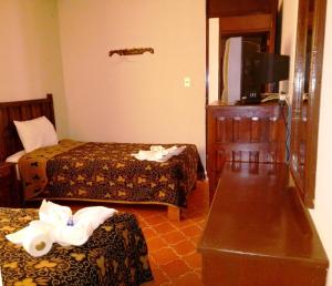 a hotel room with two beds and a television at Hotel Posada del Cortijo in Morelia