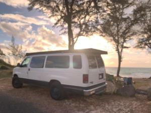 a white van parked on the beach with the ocean at Camper Van Hawaii in Kaneohe