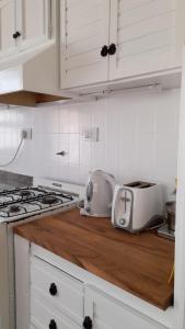 una cucina con armadi bianchi e piano di lavoro con tostapane di Meridiano Alquiler Temporario a La Plata