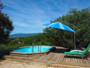 einen Pool mit einem blauen Regenschirm, einem Stuhl, einem Tisch und einem Stuhl in der Unterkunft Nice house with private pool in the Parc du Luberon, Grambois in Grambois