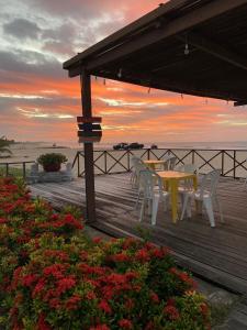 a table and chairs on a wooden deck with a sunset at Pousada Casa Do Alemão in Flecheiras