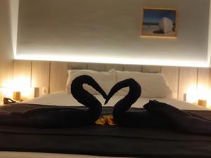Dois cisnes negros a fazer um coração numa cama em Flat Samba em Cabo Frio