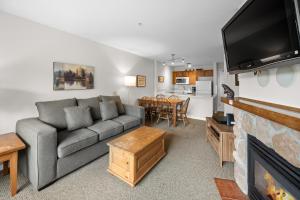 een woonkamer met een bank en een open haard bij Bear Lodge One Bedroom by MVA in Whistler