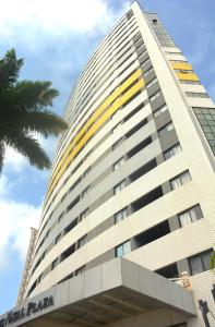 een hoog gebouw met een palmboom ervoor bij Suítes Natal Plaza - Apto 1812 in Natal