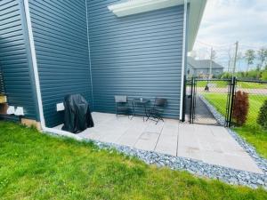 um pátio com duas cadeiras e uma mesa ao lado de uma casa em Beautiful 1 bedroom apartment - private entrance em Moncton