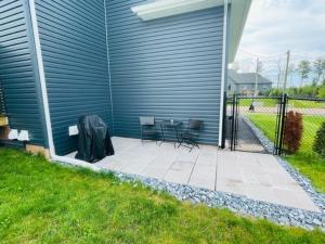 a patio with two chairs and a table next to a house at Beautiful 1 bedroom apartment - private entrance in Moncton