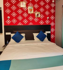 a bed with blue and white pillows and a red wall at Udupi Comforts in Udupi