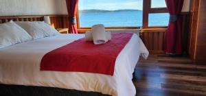 a person sitting on a bed in a room with a window at Hostal Vista al Mar hct in Ancud