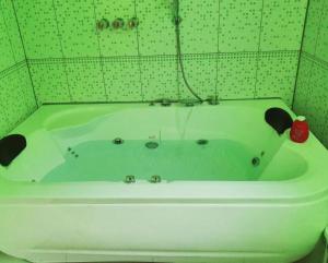 a white bath tub in a green tiled bathroom at HOTEL REY DE ORO in Chiclayo
