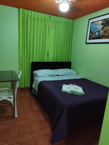 a bedroom with a bed with a table and green curtains at HOTEL REY DE ORO in Chiclayo