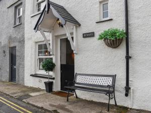 una panchina seduta fuori da un edificio bianco di Byways a Cartmel