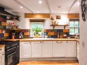 a kitchen with white cabinets and a sink at Bridge Cottage in Porkellis
