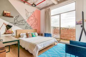 a bedroom with a bed and a desk and a window at Socialtel Candelaria Bogotá in Bogotá