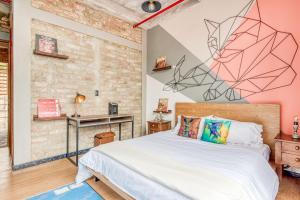 a bedroom with a bed and a wall with a painting at Socialtel Candelaria Bogotá in Bogotá