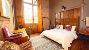 a bedroom with a bed and a desk and window at Socialtel Candelaria Bogotá in Bogotá