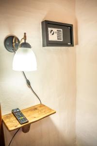 una lámpara en una pared con un mando a distancia en un estante en El Campo en Sierra de la Ventana