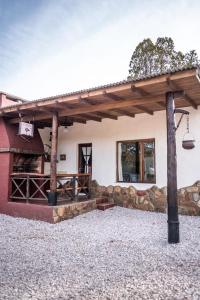 a building with a wooden roof and a stone wall at El Campo in Sierra de la Ventana