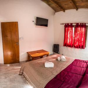 1 dormitorio con cama, mesa y cortinas rojas en El Campo en Sierra de la Ventana
