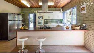 a large kitchen with a counter and stools in it at Casa das Águas - São Francisco Xavier in São Francisco Xavier +10 photos