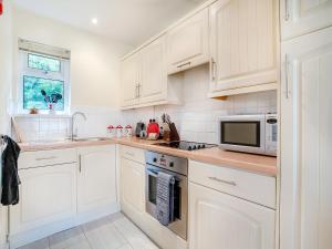 a white kitchen with white cabinets and a microwave at Trem Yr Afon in Ciliau-Aeron