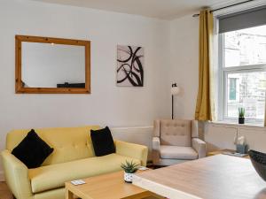 a living room with a yellow couch and a chair at The Hamilton Collection - Waterloo Place in Spittal