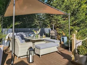a patio with an umbrella and a table and a grill at Harperfield Chalet in Lanark