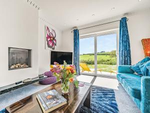 a living room with a blue couch and a fireplace at Pentire in Holbeton