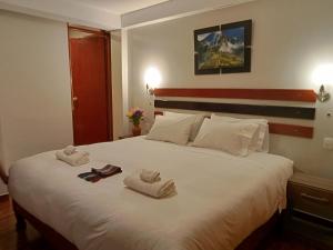 a bedroom with a large white bed with towels on it at Raymi Inn MachuPicchu in Machu Picchu