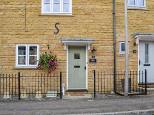 a brick house with a green door and a window at Jasmine Cottage in Chipping Campden