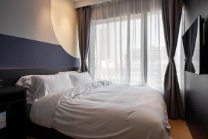 a bedroom with a white bed and a window at Dayin East Nanjing Road & The Bund in Shanghai