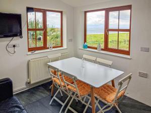 - une salle à manger avec une table, des chaises et des fenêtres dans l'établissement Ceiliog Bach, à Llangennith