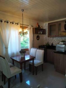 cocina con mesa de madera y sillas blancas y comedor en chalé do Riacho en Gramado