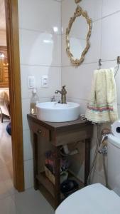 a bathroom with a sink and a toilet and a mirror at chalé do Riacho in Gramado