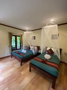 Khao Sok River & Jungle Bungalow في خاو سوك: سريرين في غرفة ذات أرضيات خشبية