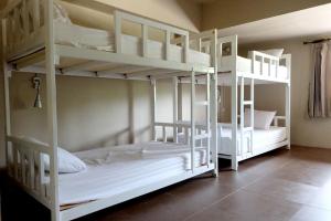 two white bunk beds in a room at Non La Mer Hostel - Bed & Yoga in Ko Lanta