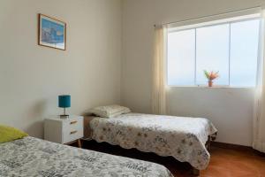1 dormitorio con 2 camas y una ventana con una planta en Magnífica Casa de playa 3BR, en Lurín