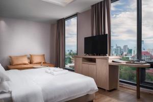 a hotel room with a bed and a tv at SF HOTEL Penthouse Residences in Phnom Penh