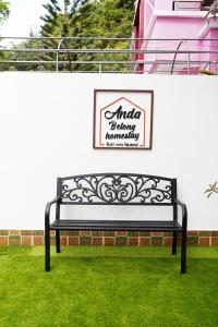 a black bench sitting in the grass next to a wall at Anda Betong Homestay in Ban Komo Sip Paet