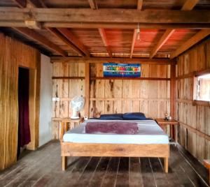 a bedroom with a bed in a wooden wall at Dragonfly Guesthouse in Koh Rong Sanloem