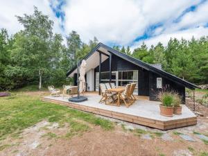 ein schwarzes Cottage mit einer Terrasse und einem Tisch in der Unterkunft Holiday home Nørre Nebel III in Nørre Nebel