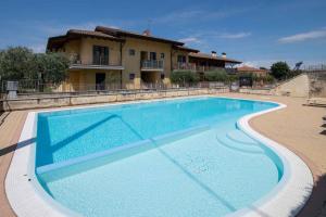 a large blue swimming pool in front of a house at Apartment in Pacengo - Gardasee 45414 in Pacengo di Lazise